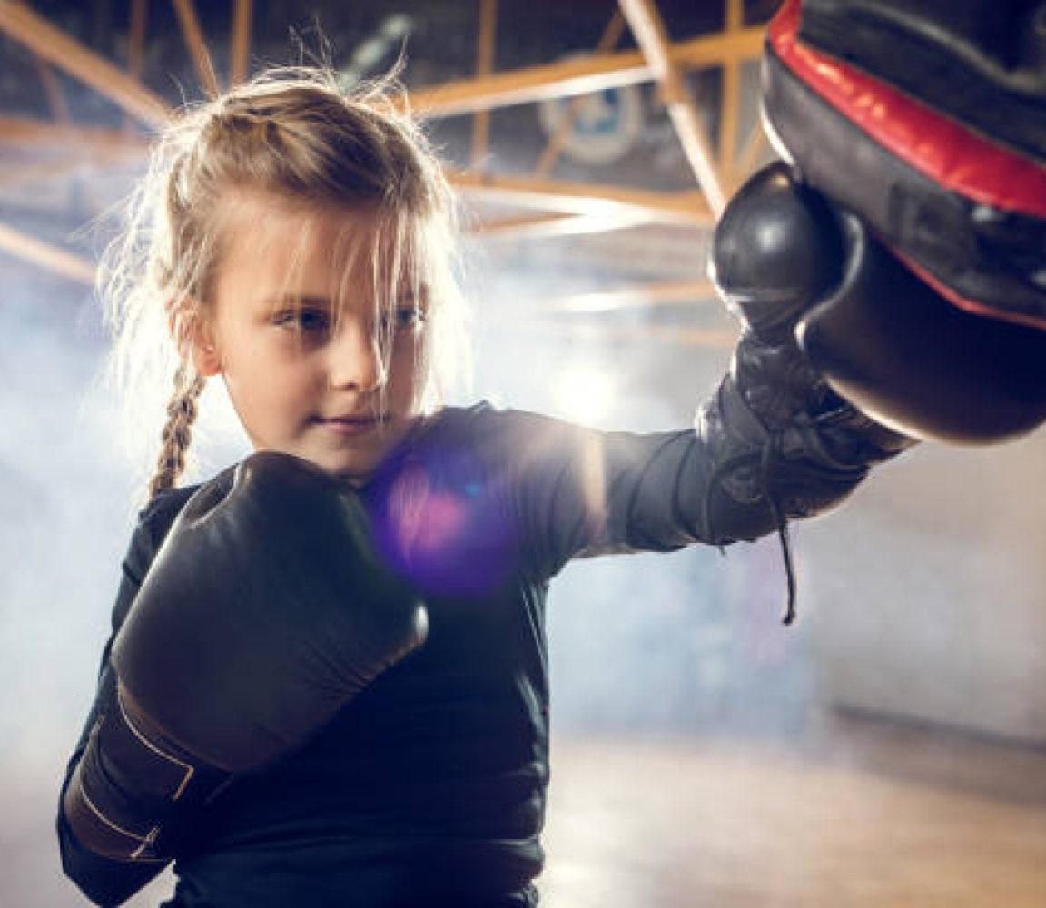 Little girl having a boxing training in a health club.